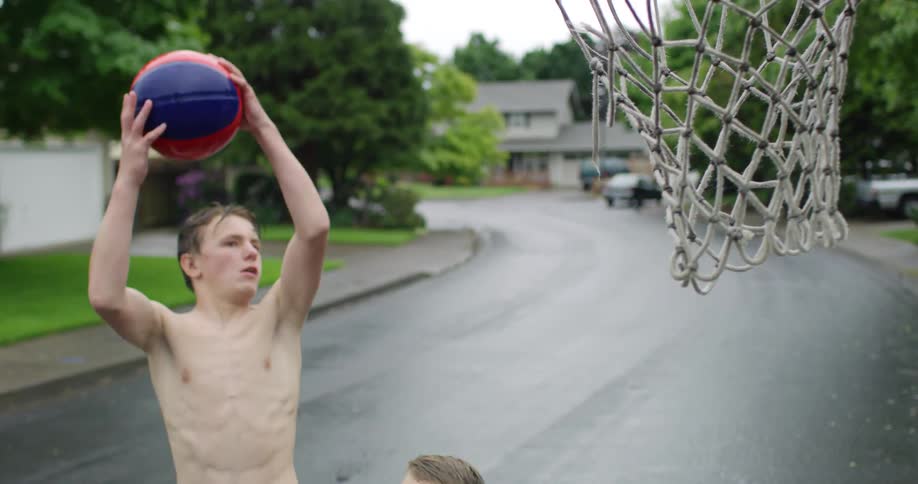 Two boys play basketball in the street