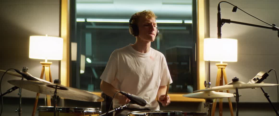 Young man playing drum kit in recording studio