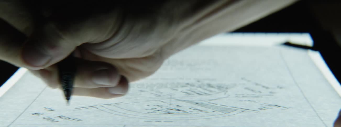 A man writes on a blueprint