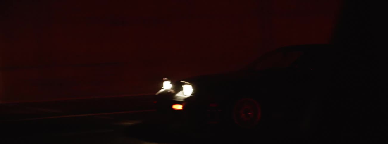 A driver in a car at night drives through a tunnel and then outdoors