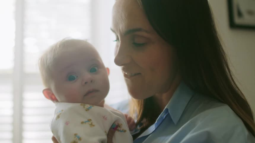 A mother holds her baby and talks and bounces up and down