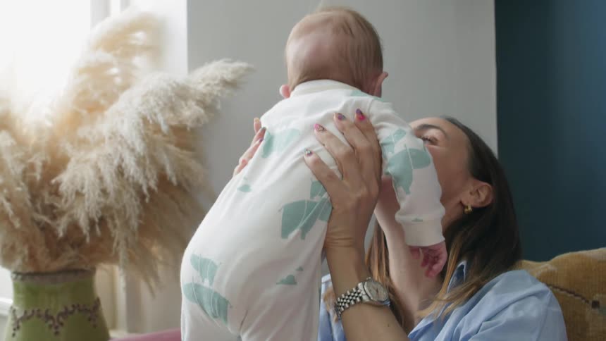 A woman sitting on a couch playing with a baby