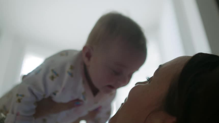 Mother playfully lifts her baby on the living room
