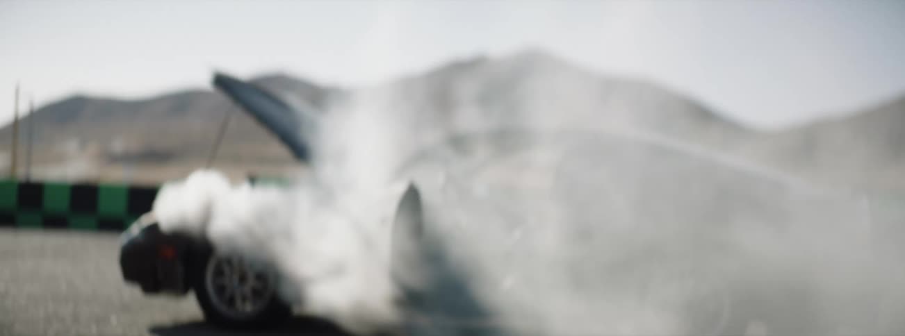 A man rubs his head as he looks back and walks away from a broken down car with smoke billowing out of it
