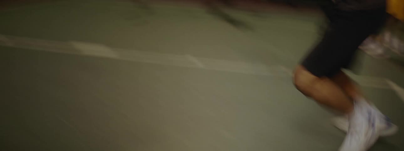 Men play basketball in the basketball court at night