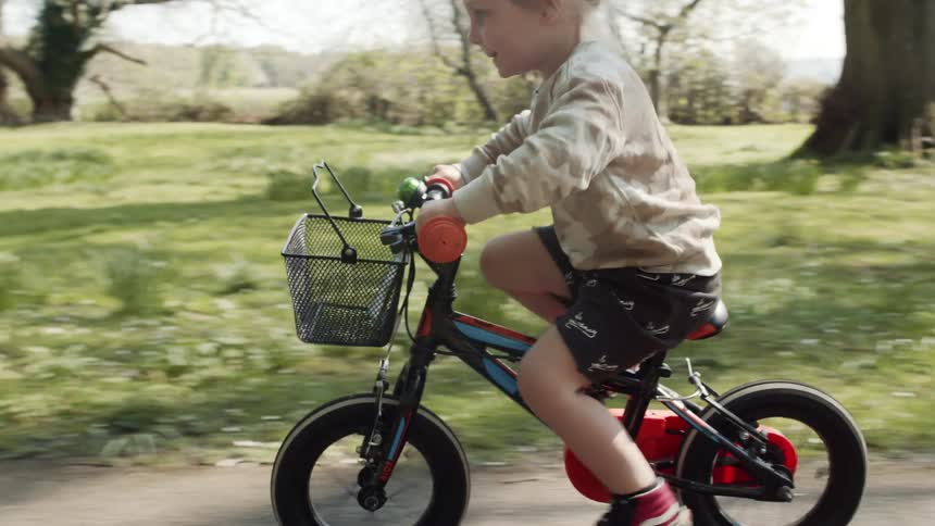 Young child riding bicycle down paved rural road