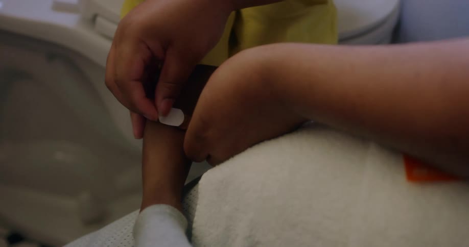 An adult applying a small bandage to the leg of a child