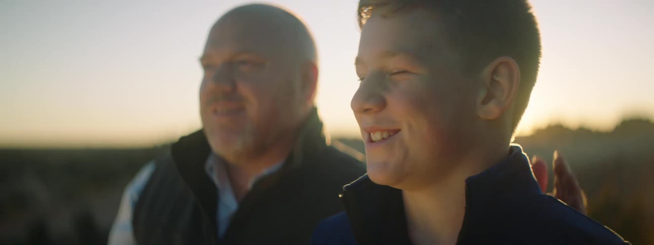 A father pats his son on the back as he points something out to him