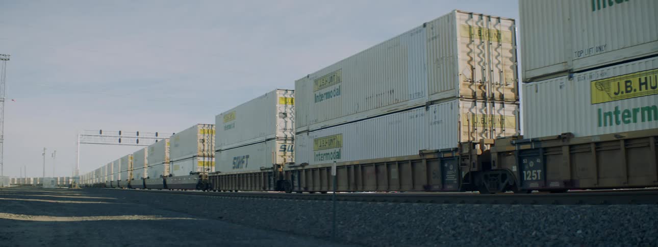 Shipping containers are stacked next to train tracks