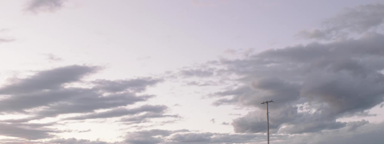 The power line pole rises into the cloudy sky