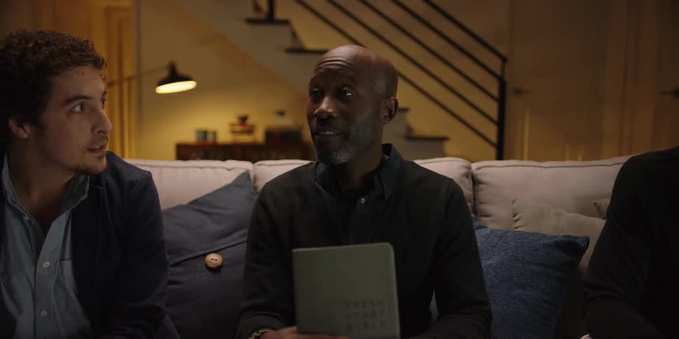 Three men sit together on a couch having a discussion