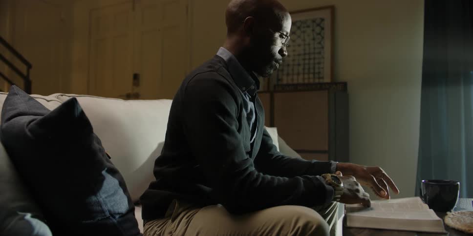 Black man turns over the pages of a book and sips his cup