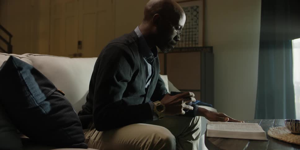 Man sitting on couch drinking coffee and reading book