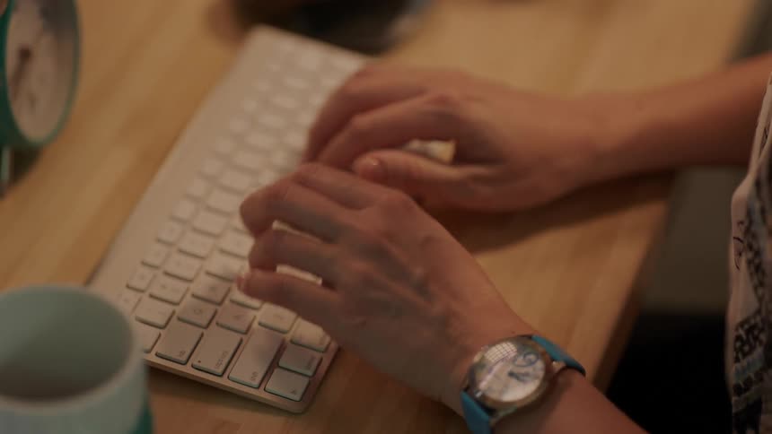 A person is typing on their keyboard at a desk