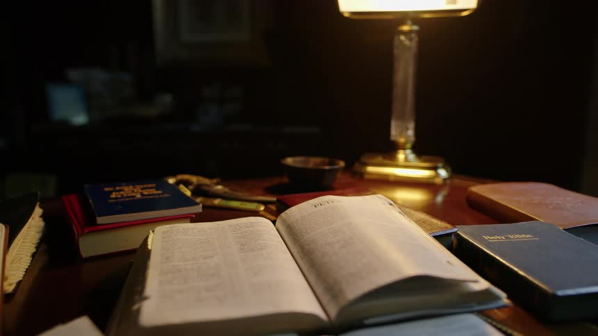 Several bibles on desk under desk lamp