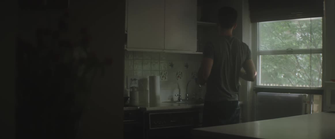 A man takes a container out of a kitchen cupboard