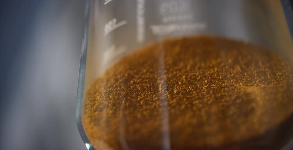 Orange powder fills the bottom of a glass flask