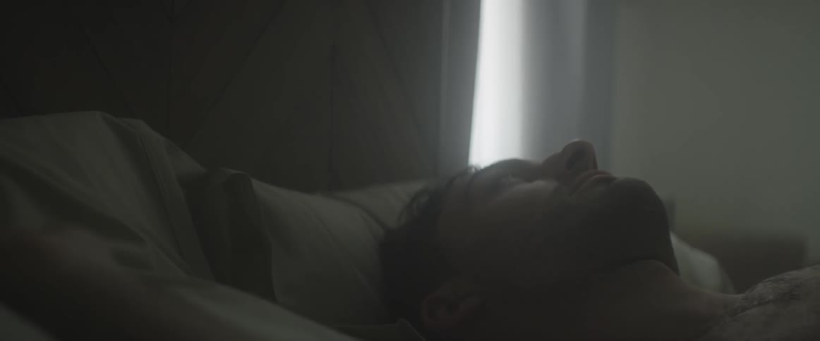 A man lays in bed while staring at the ceiling