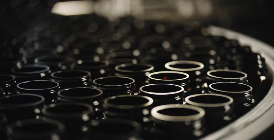 Dozens of empty pill bottle containers move on a conveyor belt