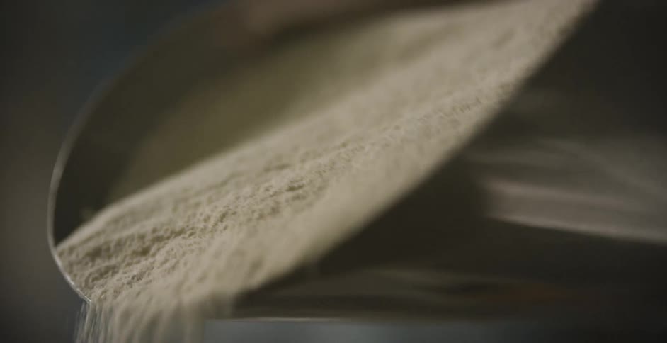 Cornmeal being sifted as it falls off a scoop