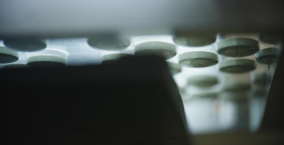Pills move by and are hit with a flash of light on an assembly line
