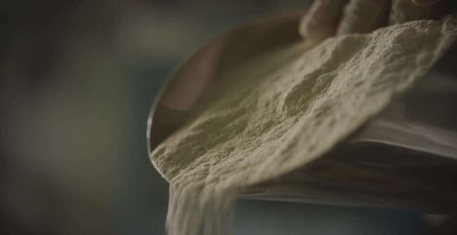 A person pushes flour out of a scoop