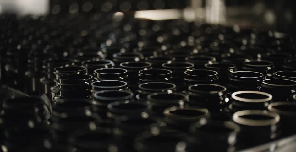 Glass pill bottles moving on a conveyor belt in a factory