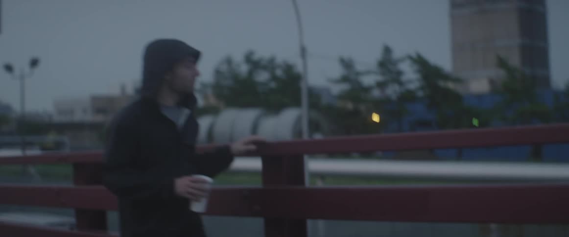A walking man carries a cup while touching the railing