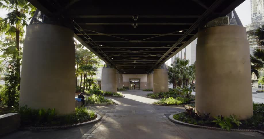 Pedestrians walking along and resting on a well kept path under a bridge in a metropolis
