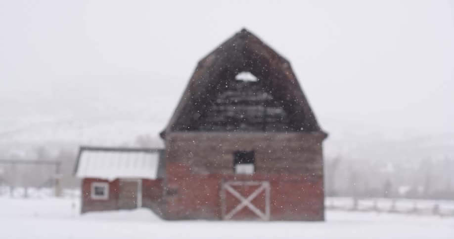 Heavy snow falls over a red barn