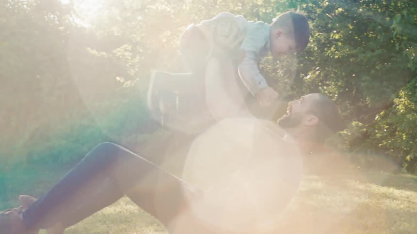 Father and son play on the green grass in the garden