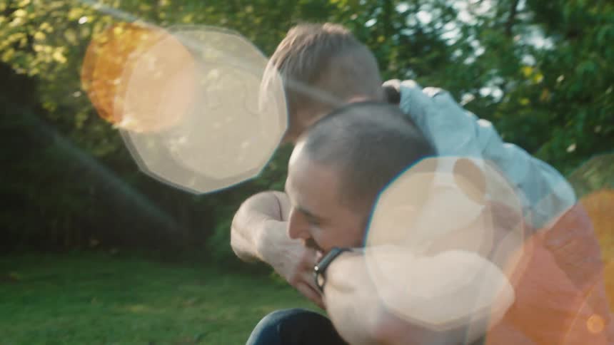 Father and son play together on the grass in the garden