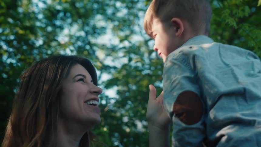 Son kisses his mother on her lips in the garden