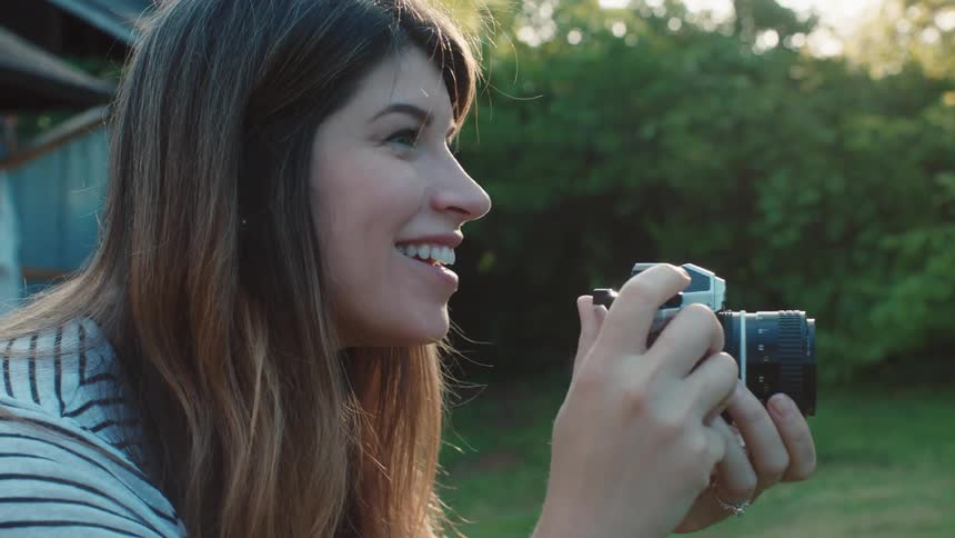A woman smiles as she takes photographs