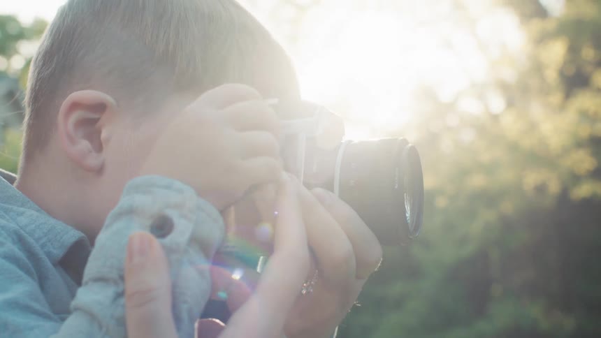 A mother helps her son use a camera