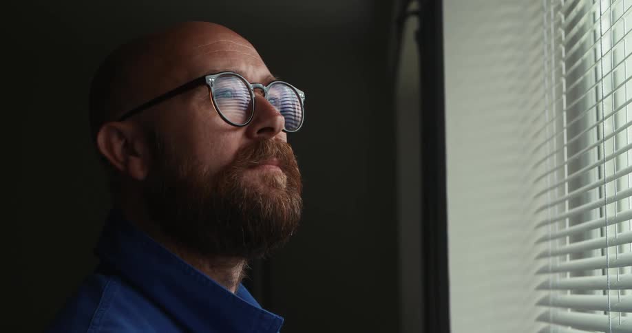 A man stands and looks out a window