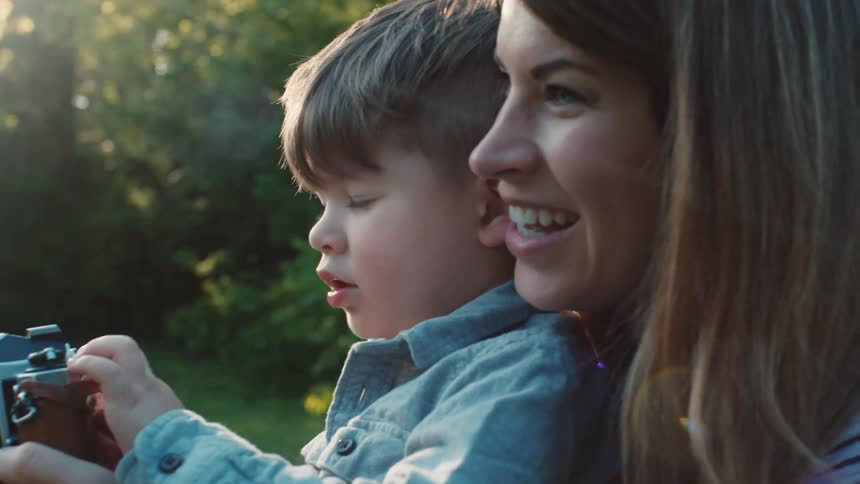 A woman helps her son use a camera