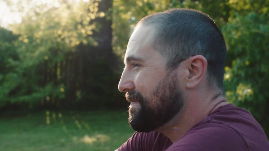 A man is smiling while sitting outside