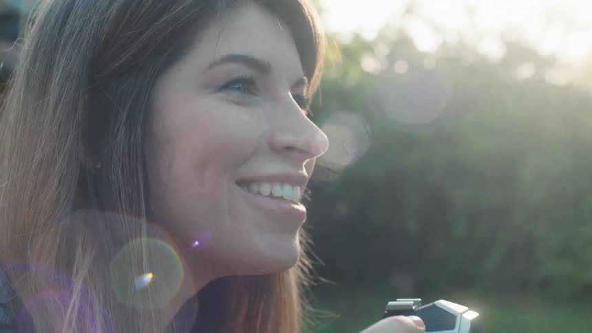 Woman smiles and takes a photograph of her family in the garden