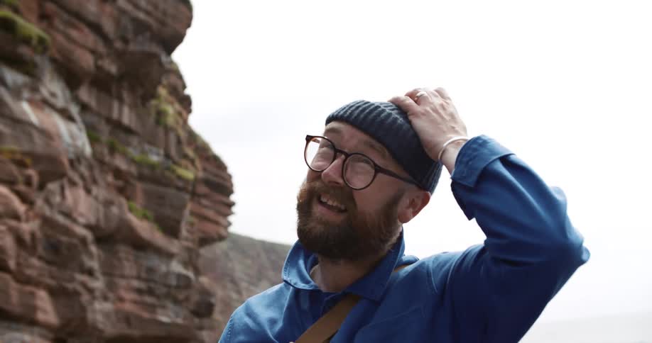 A man stands in front of a canyon and then looks around him