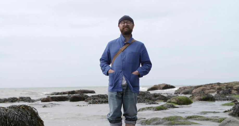 Man stands in the water and poses for the camera by the sea