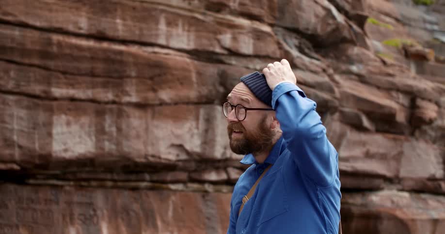 A man hiking turns around and removes his hat