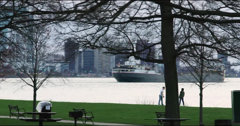 Two people stand by a city lake in a public park