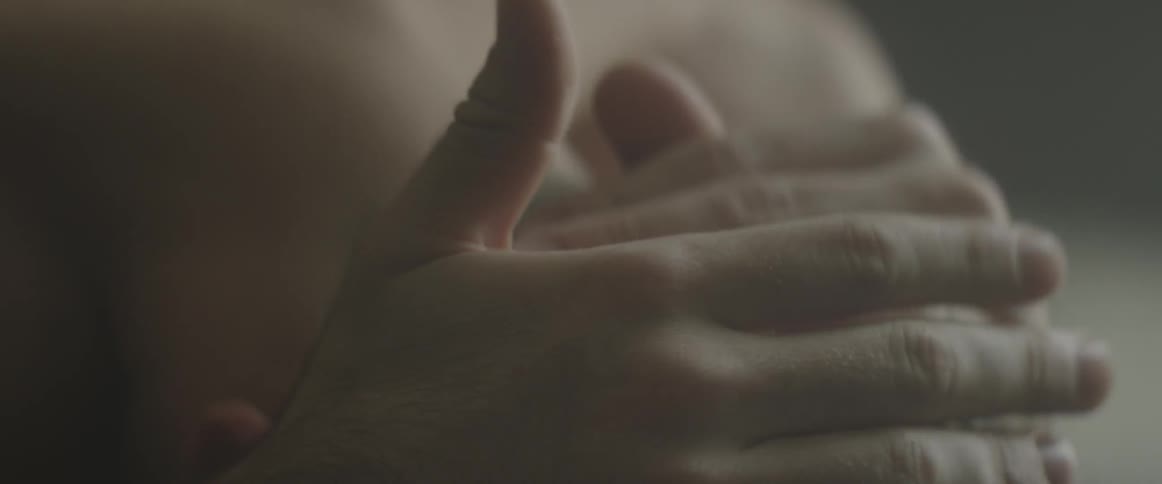 A man rubs his head and lifts up in a dim room