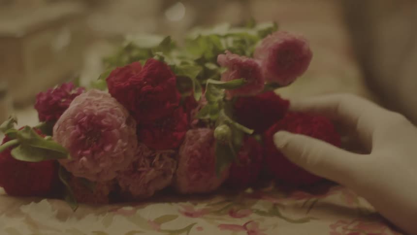 A woman's gloved hand caresses a bouquet of flowers