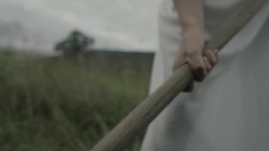 A woman digs a hole in a grassy field