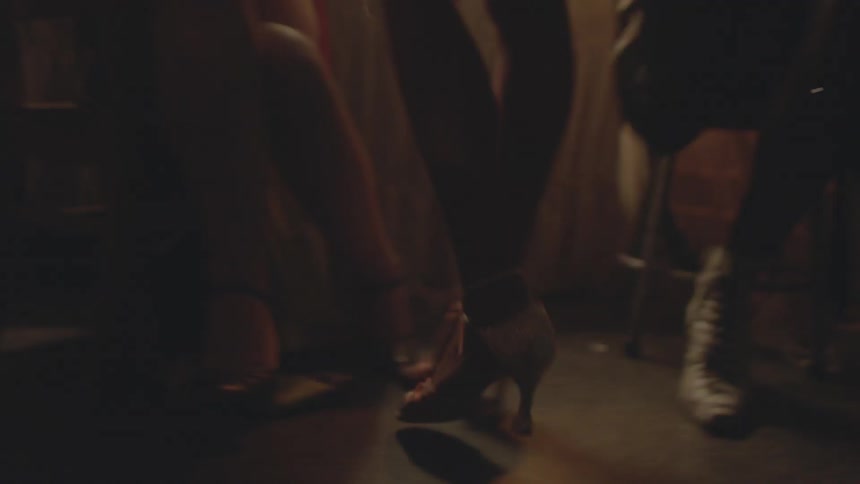 A woman in sparkling shoes walks into a group of other women