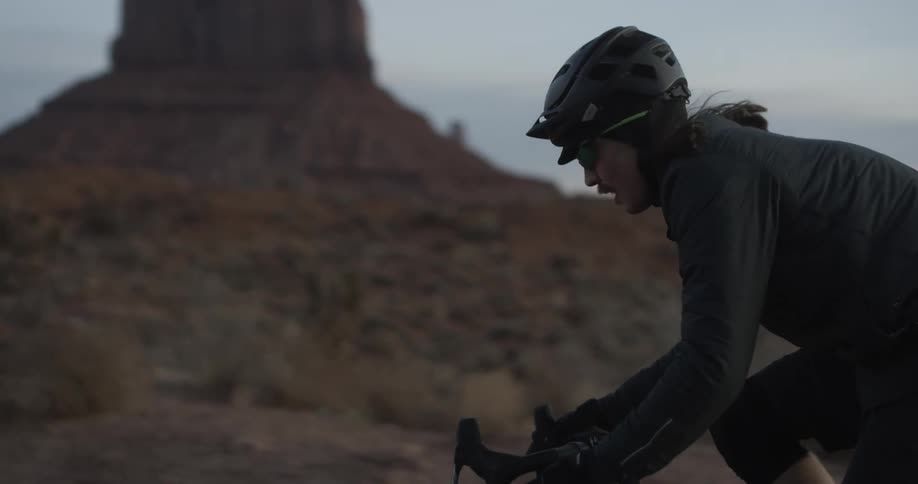 Male cyclist cycles on the dirt road at dusk