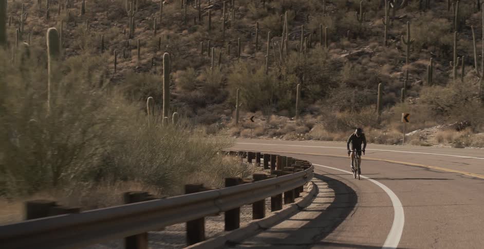 A cyclist rides a bike on a desert mountain road