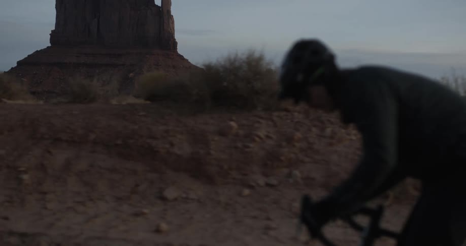 A man rides a bicycle through a desert